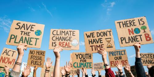 Varias manos alzan pancartas con eslóganes relacionados con el cambio climático Varias manos alzan pancartas con eslóganes relacionados con el cambio climático