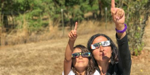Mujer y niña observan un eclipse solar equipadas con las gafas necesarias para ello.