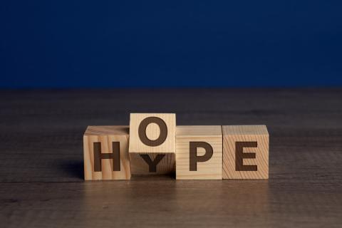 Bloques de letras de madera con las letras 'HOPE'. El bloque de la O gira mostrando una Y y la palabra 'HYPE'.